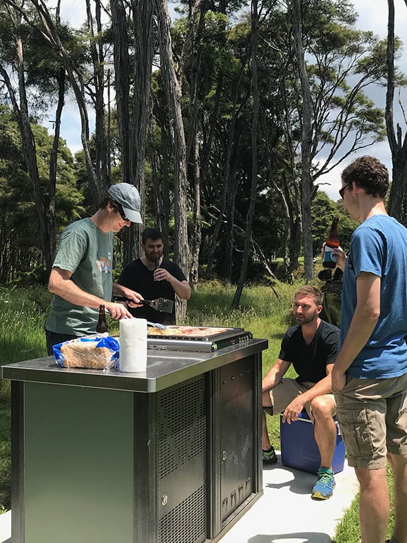 Photo of the Springtimesoft team members cooking at a barbeque with trees in the background