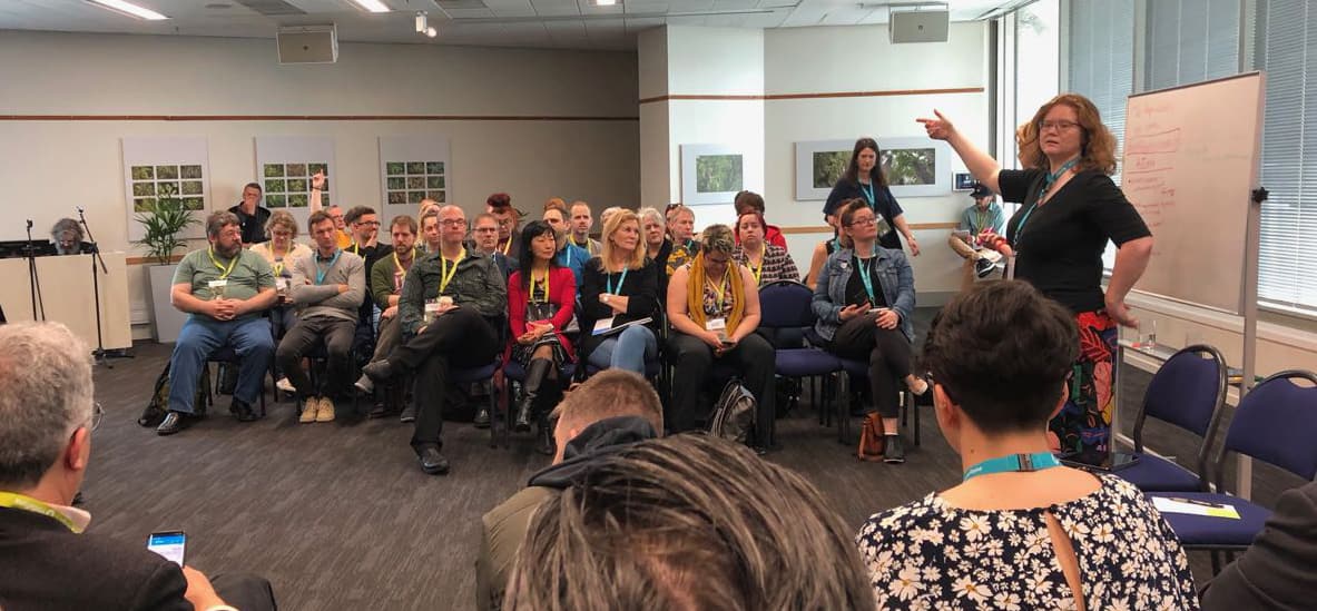 Photo of a group of people in a discussion forum with a woman standing and speaking