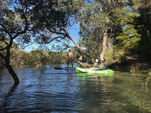 Perrin standing on a paddleboard next to Ben in a kayak